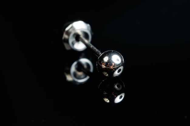 Silver earring macro photo with a precious stone on a black isolated background