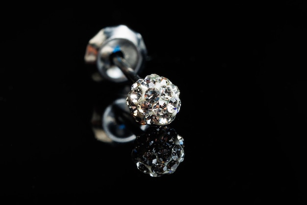 Silver earring macro photo with a precious stone on a black isolated background