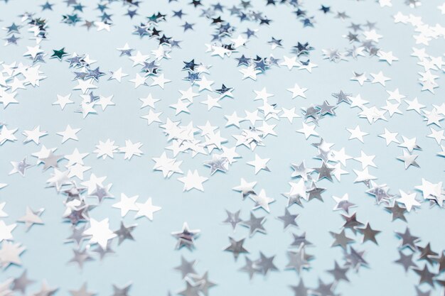 Silver foil confetti stars on blue background