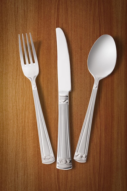 Silver fork, knife and spoon over wooden table