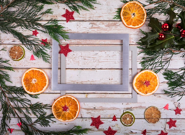 A silver frame with copy space for text in Christmas decor with Christmas tree, dry orange over old table