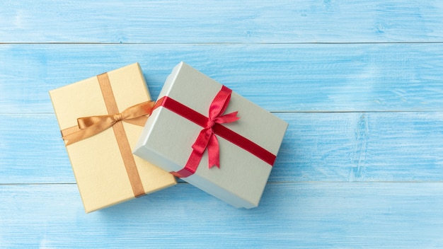 Silver and gold gift box on a blue wooden table.