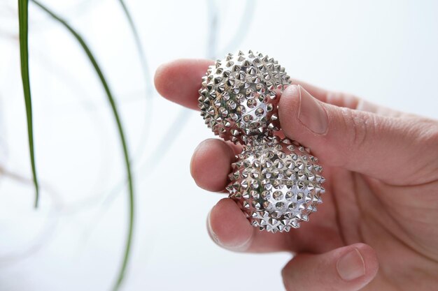 Silver metal magnetic balls in female hand spiky tool for hand massage closeup on middleaged hand