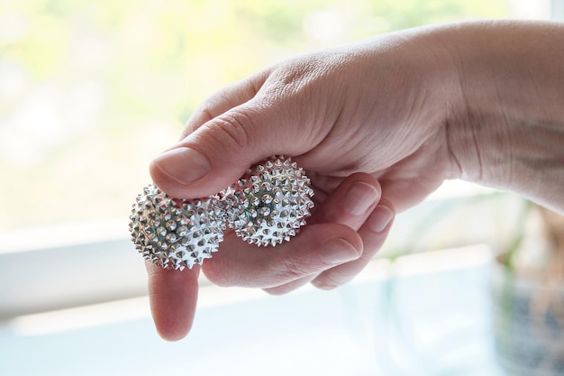 Silver metal magnetic balls in female hand Spiky tool for hand massage Closeup on middleaged hand