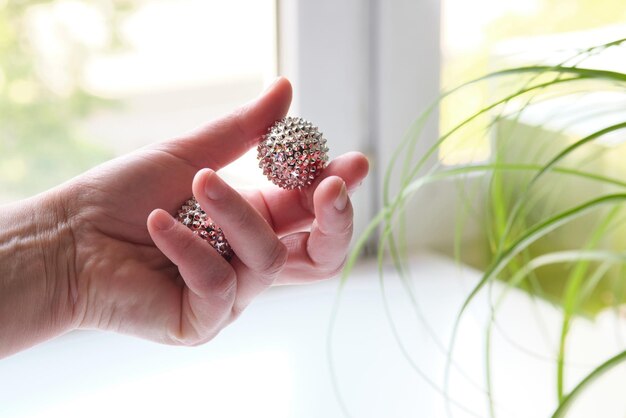 Silver metal magnetic balls in female hand spiky tool for hand massage