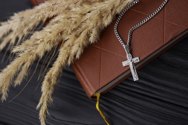 Silver necklace with crucifix cross on christian holy bible book on black wooden table Asking blessings from God with the power of holiness