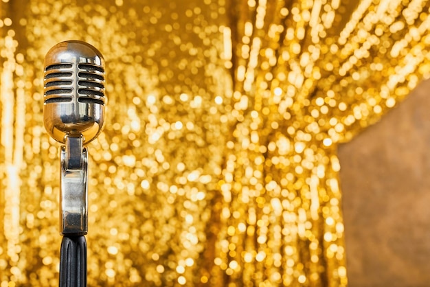 Silver retro icrophone against the background of a sparkling golden curtain