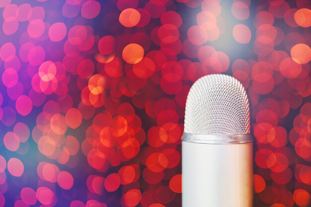 Silver retro microphone on stage with bokeh light background close up with copy space of mic in conc...