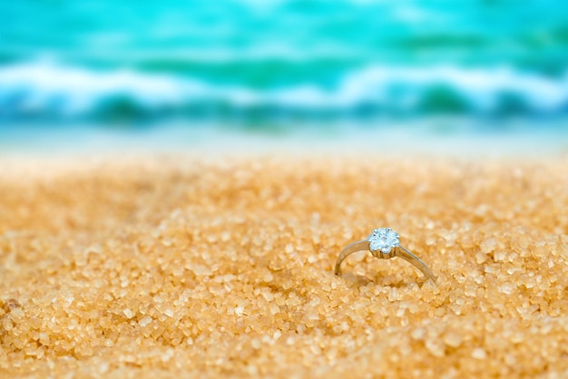 Silver ring with crystal in the sand on the background of beach and sea