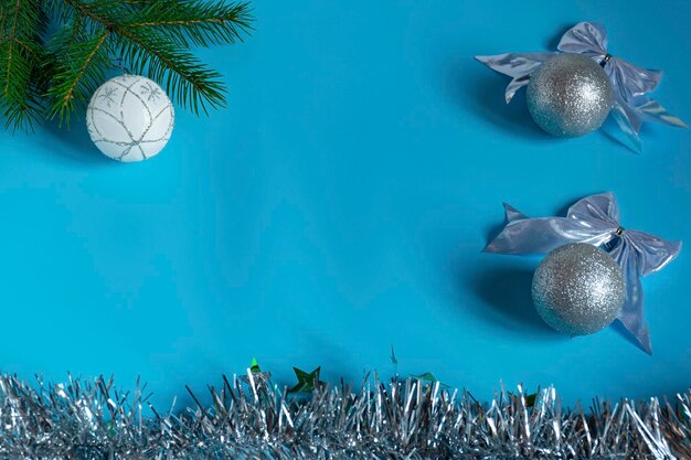 Silver shiny Christmas decorations spruce branch balls for the Christmas tree bows tinsel on a blue background top view