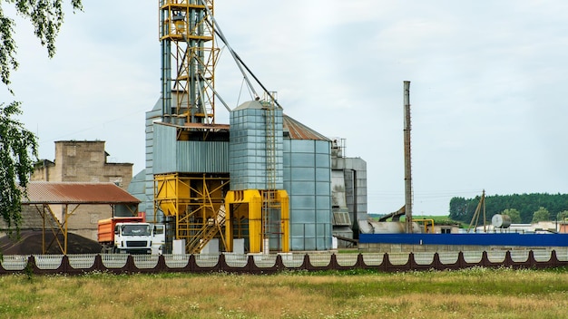 Silver silos on agro manufacturing plant for processing drying cleaning and storage of agricultural products flour cereals and grain Large iron barrels of grain Granary elevator