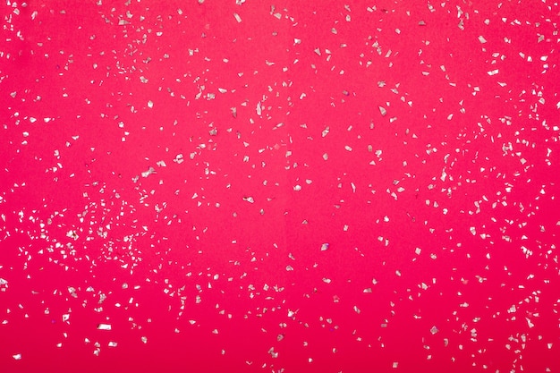 Silver sparkles scattered randomly on a pink background