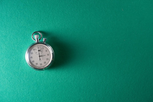 Silver stop watch against green background