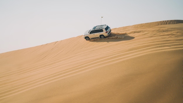 A silver suv driving on a sand dune in the desert