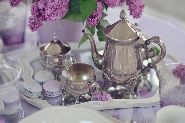 A silver tea set on a tray with purple flowers.