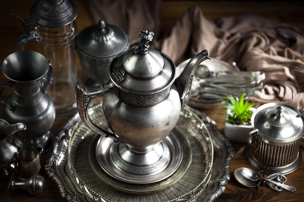 A silver teapot and silver tray with silverware on it.