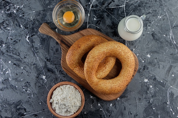 Simit with sesame seeds and a glass bowl of flour with uncooked chicken egg