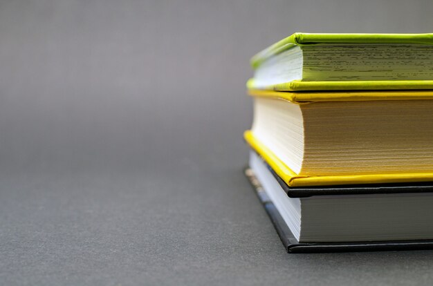 A simple composition of many hardback books on a black background. Back to school. Education concept. Copy space.