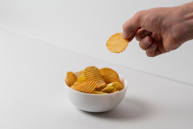 Simple concept of junk food hand pick a single potato chip from bowl