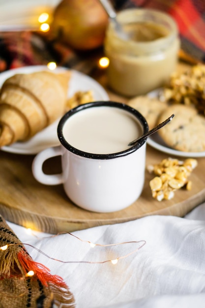 Simple country home breakfast in bed coffee with milk and homemade pastry on plaid blanket