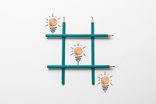 A simple creative idea of drawn paper light bulbs in the tic tac toe grid made of crayons on pastel background