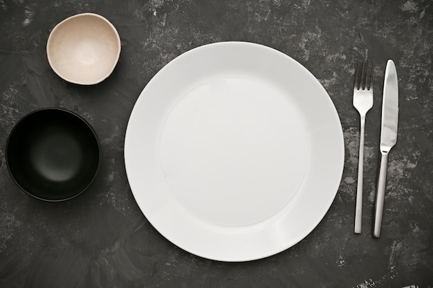 Simple dining table setting with empty white plate mockup two sauce bowl and cutlery