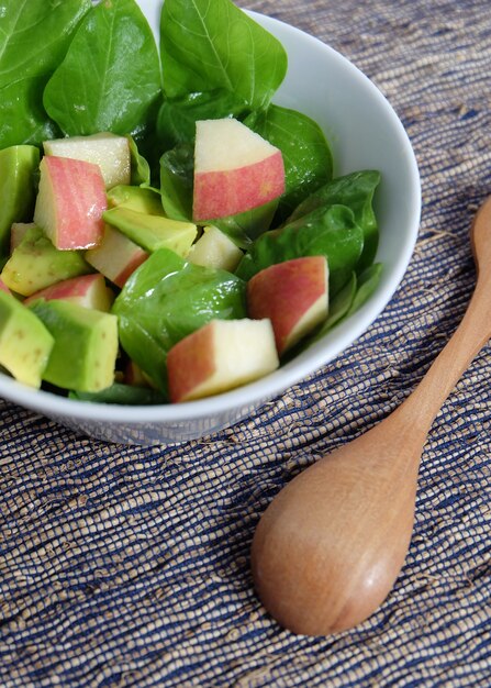 Simple salad contain spinach, apple and avocado with honey dressing.