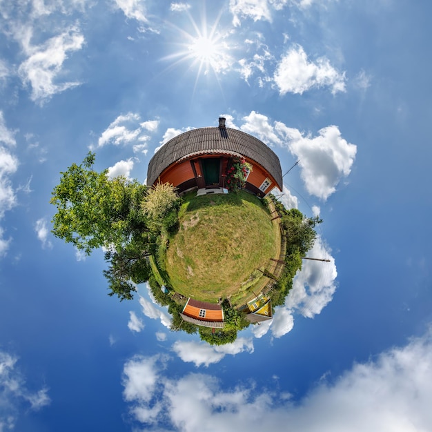 Photo simple tiny planet with wooden home or homestead building in blue sky with beautiful clouds transformation of spherical panorama 360 degrees spherical abstract aerial view curvature of space