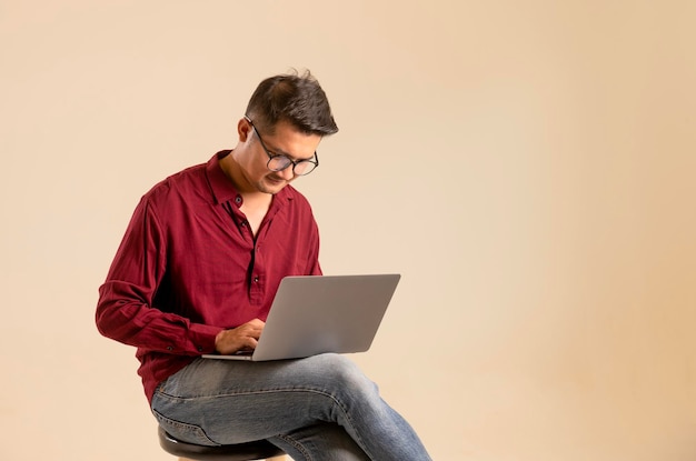 Simple young freelancer sitting working on laptop pc computer looking isolated on bright colored wall studio photo background