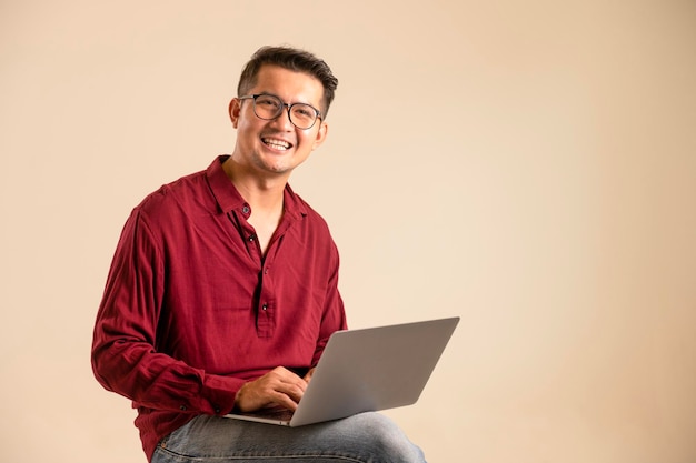 Simple young freelancer sitting working on laptop pc computer looking isolated on bright colored wall studio photo background