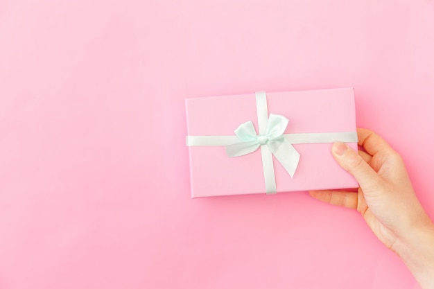 Simply design female woman hand holding pink gift box isolated on pink pastel colorful trendy background