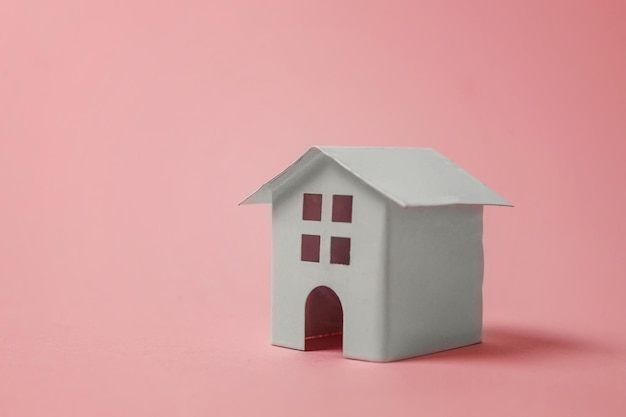 Simply design with miniature white toy house isolated on pink pastel colourful trendy background Mortgage property insurance dream home concept Copy space