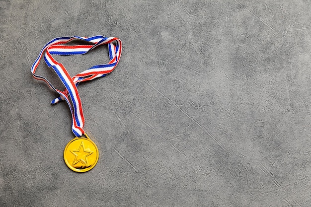 Simply flat lay design winner or champion gold trophy medal on concrete stone grey background Victory first place of competition Winning or success concept Top view flat lay copy space