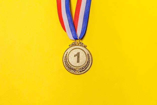 Simply flat lay winner or champion gold trophy medal isolated on yellow colorful background.