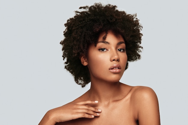 Simply stunning. Attractive young African woman looking at camera while standing against grey background