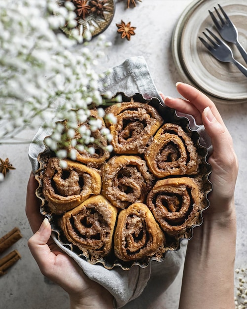 Sinabon rolls on the baking form in the women's hands. Top view