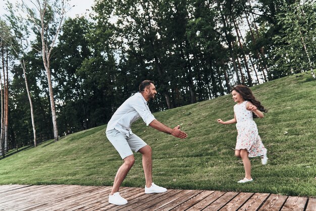 Sincere joy. Young loving father keeping arms outstretched while his smiling daughter running to him outdoors