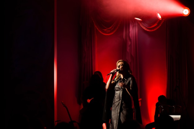 Singer with her band performing on stage. Concert. View from the auditorium.