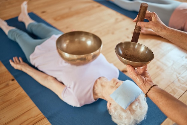 Photo singing bowls meditation and senior woman on floor for healing vibration and sound therapy with healer sound healing zen and elderly lady on a ground for tibetan bowl music relax and wellness