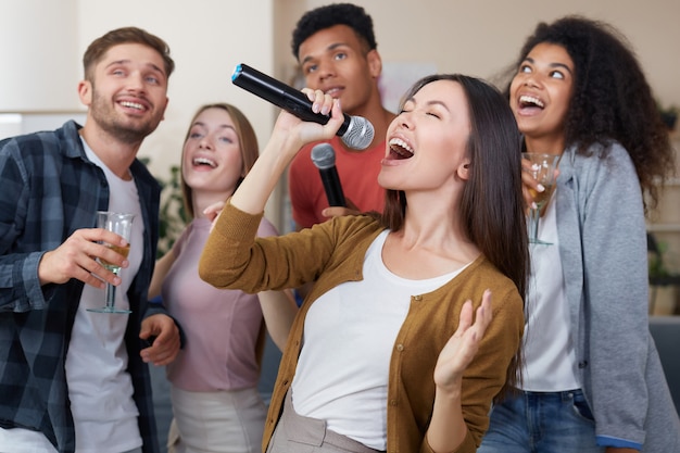 Singing girl young beautiful asian woman holding microphone and singing while having fun with