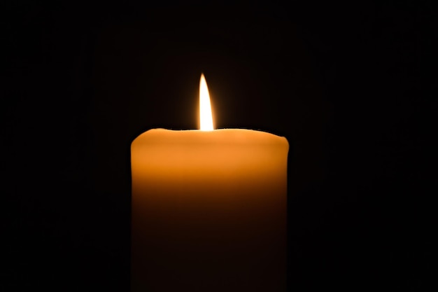 Single candle burning burning brightly in the black background