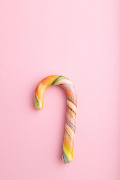 Single cane candy on pink background copy space top view