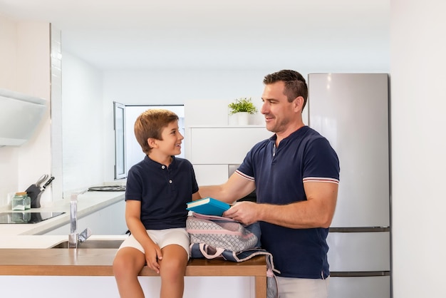 Single father preparing son's backpack before going to school Single parent family First day school