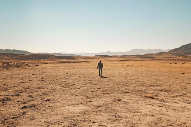 Photo a single figure walking through the vast desert