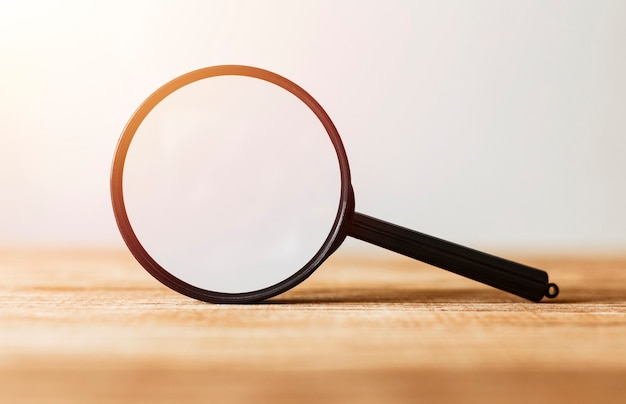 Single Magnifying Glass with Black Handle, Leaning on the Wooden Table.