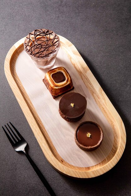 Photo single origin chocolate flight toasted marshmallow chocolate tart cacao chocolate puff balls chocolate tart round with fork served in dish isolated on dark background top view of baked cafe food