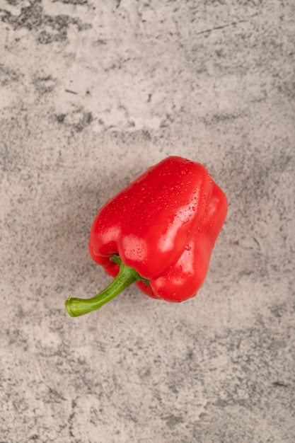 Single red bell pepper placed on stone surface