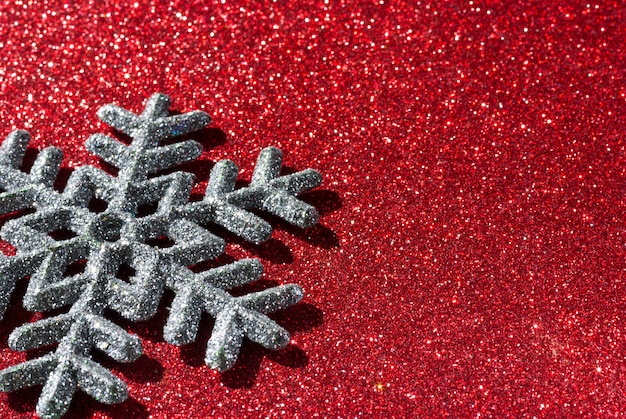 A single shiny snowflake on red glittering background