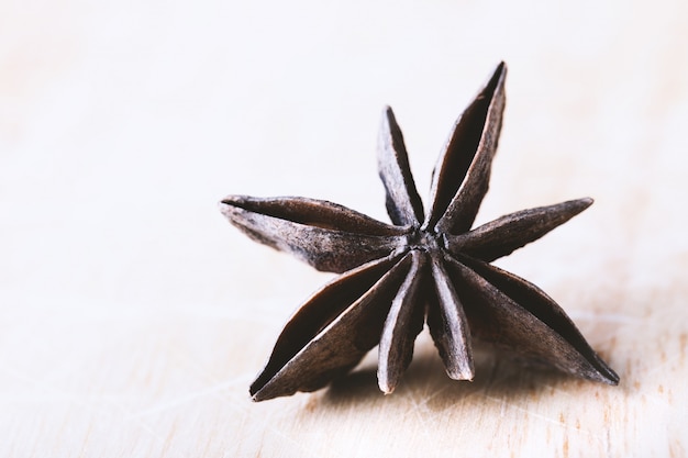 Single star anise on old wooden table close-up with copyspace.