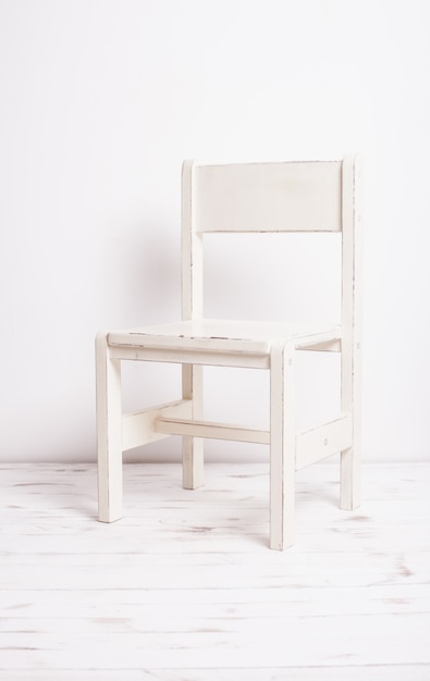 Photo single white rustic chair standing in an empty room on light wooden parquet floor.